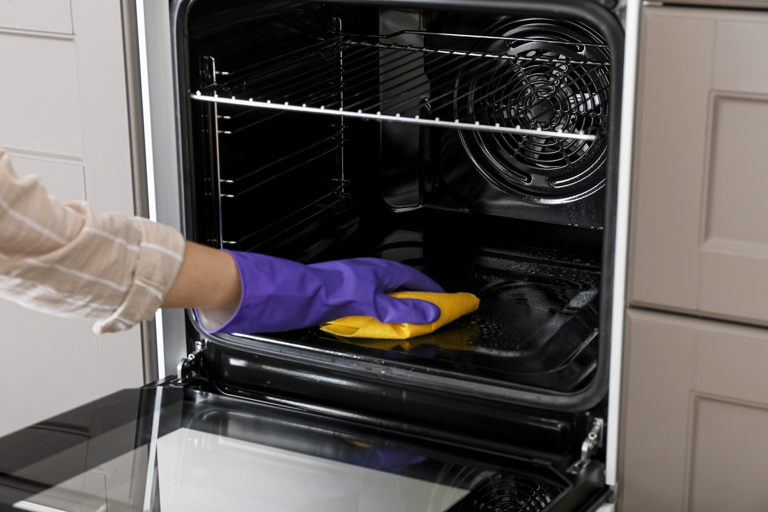 Woman Cleaning Oven in Kitchen